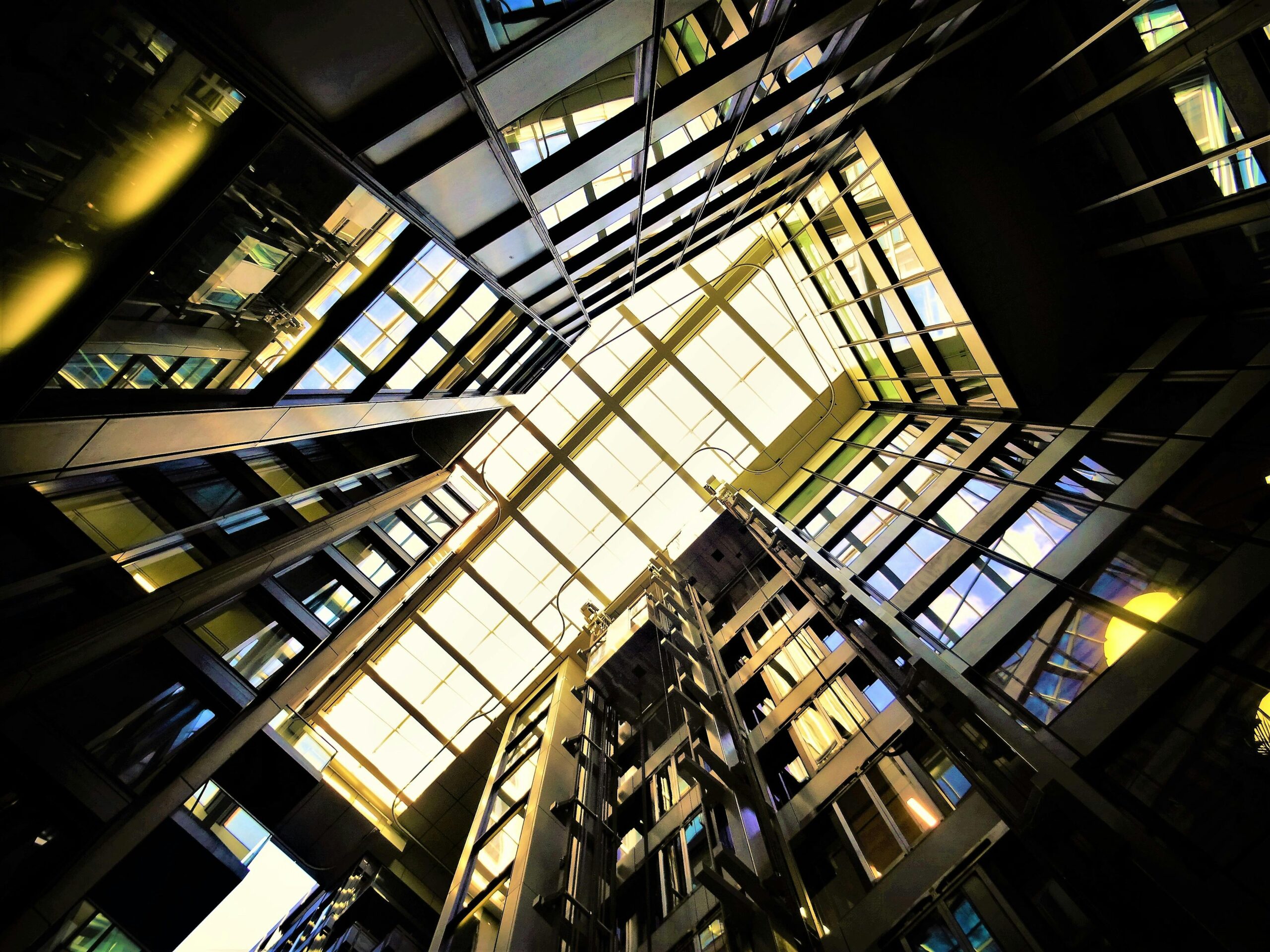 Dynamic low-angle view of a modern building's glass ceiling showcasing reflections and light.