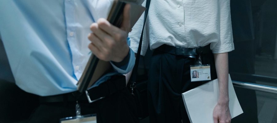 Two professionals in an elevator carrying documents, showcasing office attire.